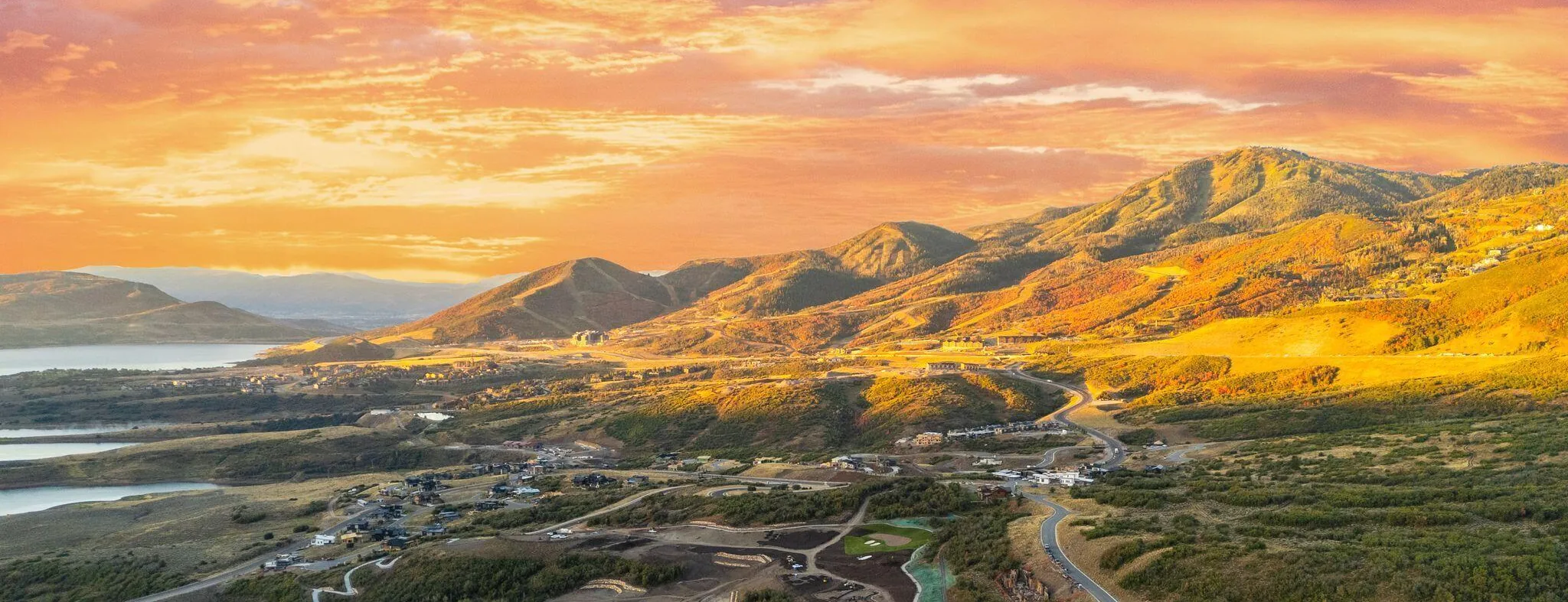 Aerial view of the SkyRidge Mountain Community at sunset, with the reservoir and mountains beyond